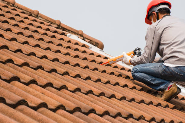 Technician man hand using glue gun with silicone adhesive or manual caulking gun with polyurethane to seal the leak on the roof. Installing and building construction concept.